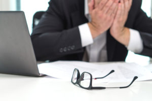 Man holding his head in his hands at his desk after experiencing age discrimination in Denver, CO