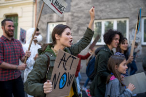 woman protesting with "act now" sign