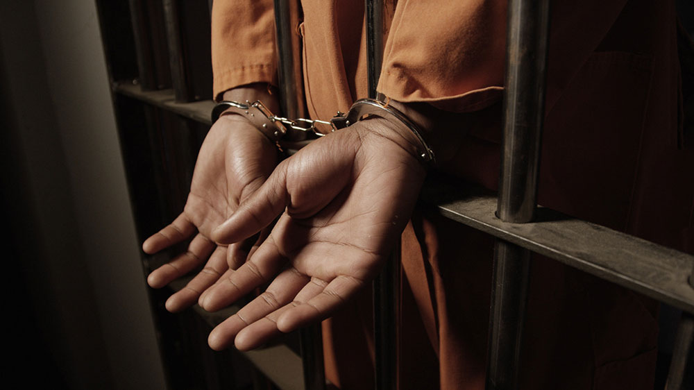 black man in handcuffs in jail cell