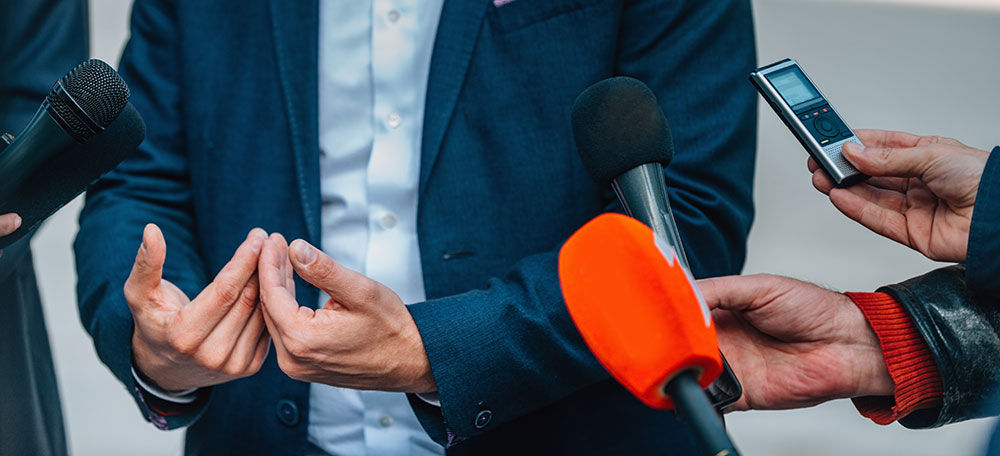 man in front of media and microphones