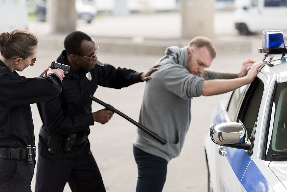 two officers arresting a man by his car; potential police misconduct